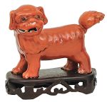 Pequena escultura chinesa em porcelana modelada em cão de fó coberto por esmalte monocromático rouge de fer. Séc. XIX. Alt. 9,5 cm ; Compr. 15 cm
