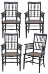 Antigo conjunto de quatro cadeiras de braços europeias, em madeira pintada de negro, apresentando tabela em fusos torneados, assento em palhinha e parte superior em arcada decorada com volutas. Alt. 91 cm