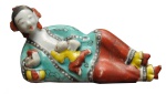 Estatueta em porcelana chinesa decorada em policromia de esmaltes representando mãe recostada com filho. Séc. XIX. Compr. 11,5 cm