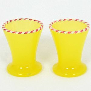 <b>Par de pequenos copos</b> em uralina francesa amarela, com borda em friso torcido em vermelho e branco. Séc. XIX. Alt. 6,5 cm