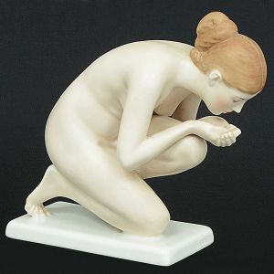 <b>Estatueta</b> em porcelana alemã Rosenthal representando figura feminina agachada. Assinada Ernst Wenck. Base em acrílico. Alt. da estatueta s/ a base 15 cm; Compr. 12 cm