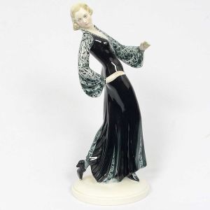 <b>Estatueta</b> em cerâmica policromada europeia representando modelo feminino com longo vestido em negro e cinza. Restauro na mão esquerda. Alt. 29,5 cm