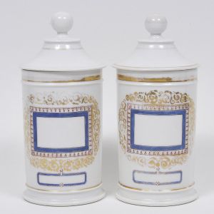 <b>Par de potes de farmácia</b> em porcelana francesa Vieux Paris apresentando reservas azuis emolduradas por arabescos violeta e ouro. Séc. XIX. Alt. 27,5 cm