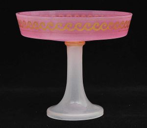 <b>Fruteira </b>circular em opalina francesa. Parte superior na cor rosa decorada com ondulações a ouro e base alongada em branco leitoso. Séc. XIX. Alt. 19,5 cm; Diâm. 22 cm