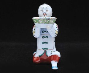 <b>Estatueta</b> em forma de figura chinesa ajoelhada, em porcelana húngara HEREND, decorada em policromia com flores e cesto às mãos. Marca da manufatura na base. Alt. 17 cm