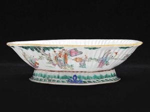 <b>Covilhete</b> oblongo em forma de trevo, em porcelana chinesa do início do séc. XIX, decorado com policromia com vários personagens em cena de exterior. Base em arabescos. Med. 8 x 25,5 x 20 cm